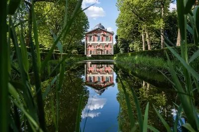 an old building reflected in the water of a canal at Paviljoen De Notelaer in Bornem