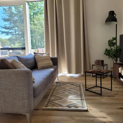 a living room with a couch and a large window at Vakantiewoning aan het water, vissen, wandelen en genieten in de natuur in Geel