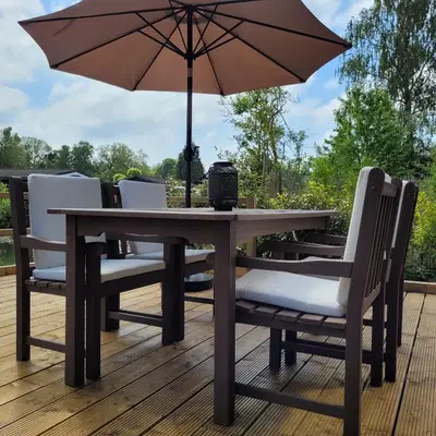 a wooden table with chairs and an umbrella on a deck at Vakantiewoning aan het water, vissen, wandelen en genieten in de natuur in Geel