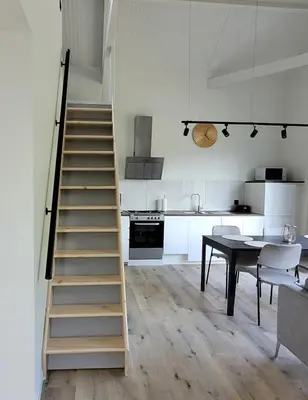 a staircase in a room with a table and a kitchen at Vakantiewoning aan het water, vissen, wandelen en genieten in de natuur in Geel