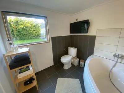 a bathroom with a tub and a toilet and a window at Huisje in Begijnendijk