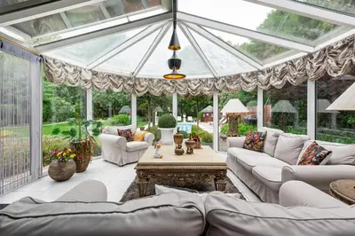 a conservatory with white furniture and a glass ceiling at thomas van der vekenlaan in Brecht