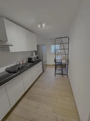 a kitchen with white cabinets and a wooden floor at Gent-cosy-stay in Ghent
