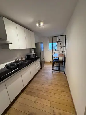 a kitchen with white cabinets and a wooden floor at Gent-cosy-stay in Ghent