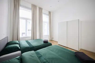 a bedroom with two green beds and a large window at Toison d'Or & Sauna in Brussels
