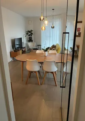 a dining table and chairs in a living room at TML Riverside Appartment 2 Bedrooms in Boom