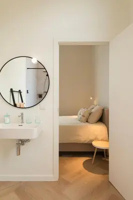 a bedroom with a bed and a sink and a mirror at NOX Logies, vakantiewoning en polyvalente ruimte in Grimbergen