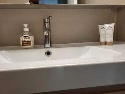 a bathroom sink with a bottle of soap and a soap dispenser at Nice studio EU Quarter in Brussels