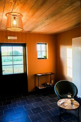 a room with a chair and a table and a window at B&B Heinehoeve in Kaprijke