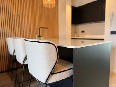 a kitchen with a counter with four white chairs at Stylish Penthouse in BXL with 2 Panoramic Terraces in Brussels