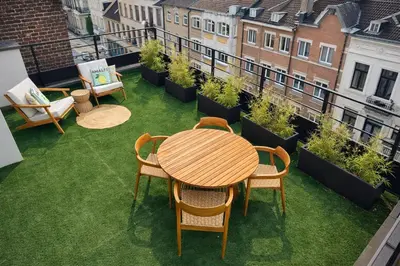 a patio with a table and chairs on a balcony at Stylish Penthouse in BXL with 2 Panoramic Terraces in Brussels