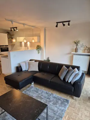 a living room with a black leather couch and a table at Huis ALNA 7 in Mechelen