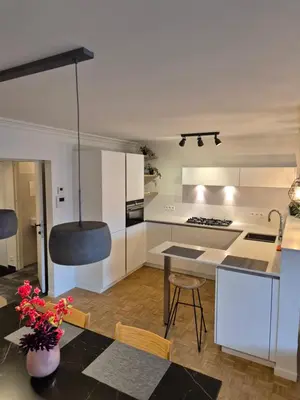a kitchen with white cabinets and a table and chairs at Huis ALNA 7 in Mechelen
