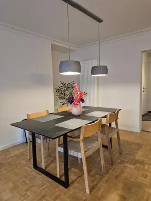 a dining room table with chairs and a vase with flowers at Huis ALNA 7 in Mechelen