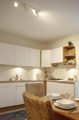 a kitchen with white cabinets and a wooden table with chairs at Sunny Stay & Chill in Brussels