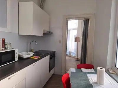 a kitchen with white cabinets and a red chair at Midi Gateway in Brussels