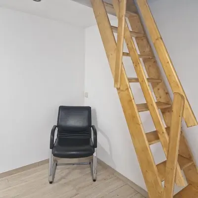 a black chair sitting next to a wooden staircase at Full apartment near Brussels and Zaventem in Vilvoorde