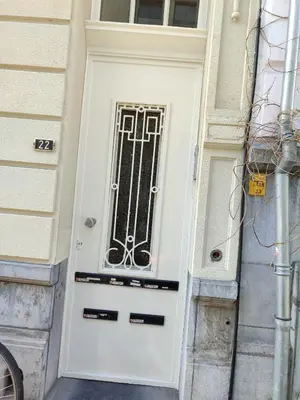 a white door with a metal grill on a building at cosy studio in Antwerp