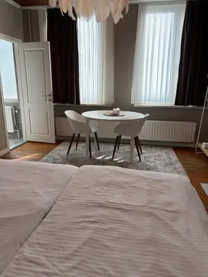 a bedroom with a table and a white bed at cosy studio in Antwerp