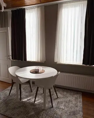a white table and chairs in a room with windows at cosy studio in Antwerp