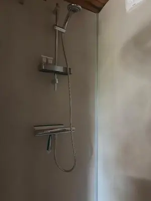 a shower with a hose hanging from a wall at PipoParel in Ravels