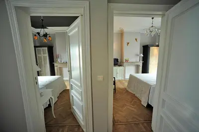 a white bedroom with two beds and a hallway at Guesthouse Expo 13 in Ghent