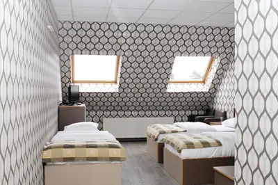 a room with three beds and two windows at Hotel Rietgors in Temse