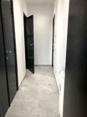 a hallway with two black doors and a tile floor at Studio 30 Pied a terre in Brussels