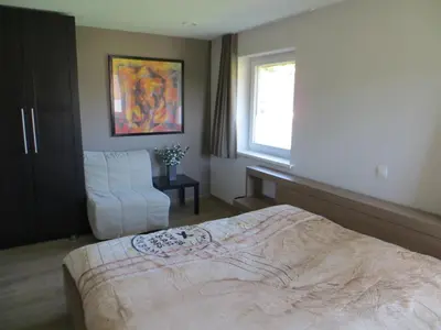 a bedroom with a bed and a chair and a window at Bed and breakfast Mentari in Ghent