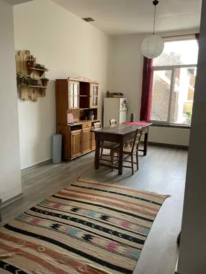 a living room with a table and a kitchen at Appartement Saint-Gilles in Brussels