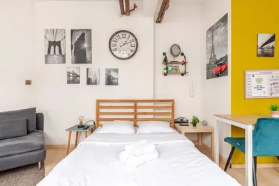 a bedroom with a bed and a desk and a clock at Cosy studio in the heart of Brussels - Grand place in Brussels