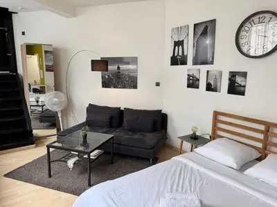 a bedroom with a couch and a clock on the wall at Cosy studio in the heart of Brussels - Grand place in Brussels