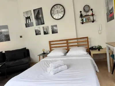 a bedroom with a bed and a clock on the wall at Cosy studio in the heart of Brussels - Grand place in Brussels