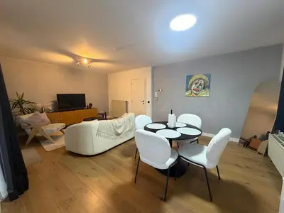 a living room with a table and white chairs at businessflat mol center in Mol