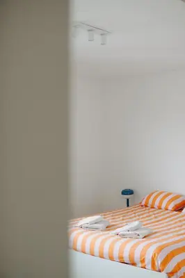 a bed with an orange and white striped blanket at Casa Congé - Colorful Stay & Free Wine Bottle in Mechelen