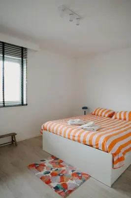 a bedroom with a bed with an orange and white comforter at Casa Congé - Colorful Stay & Free Wine Bottle in Mechelen