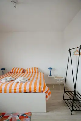 a bedroom with an orange and white bed and a chair at Casa Congé - Colorful Stay & Free Wine Bottle in Mechelen