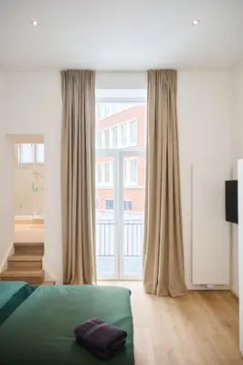 a bedroom with a bed and a large window at Louise City Center in Brussels