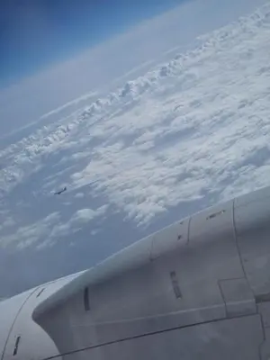 a view of the wing of an airplane flying above the clouds at Money Home in Ghent