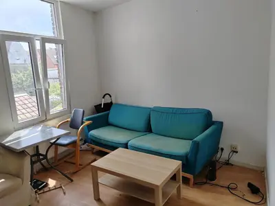 a living room with a blue couch and a table at Belgie in Ghent