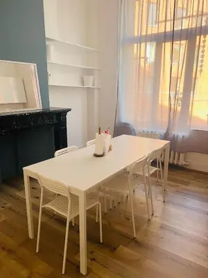 a white dining room table with chairs and a fireplace at Albergue Bosquet in Brussels
