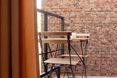a wooden chair sitting in front of a brick wall at 1 BR Stylish flat with balcony in Antwerp