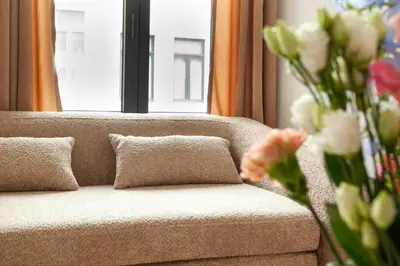 a couch with two pillows and a vase of flowers at 1 BR Stylish flat with balcony in Antwerp