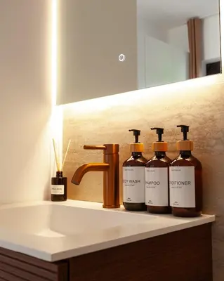 a bathroom sink with four bottles of alcohol on it at 1 BR Stylish flat with balcony in Antwerp