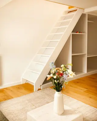 a vase of flowers sitting on a table next to a stairs at Cozy 1BDR Topfloor duplex flat in Antwerp