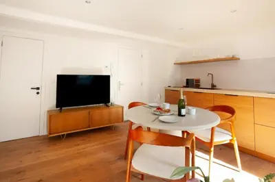 a living room with a table with chairs and a television at Cozy 1BDR Topfloor duplex flat in Antwerp