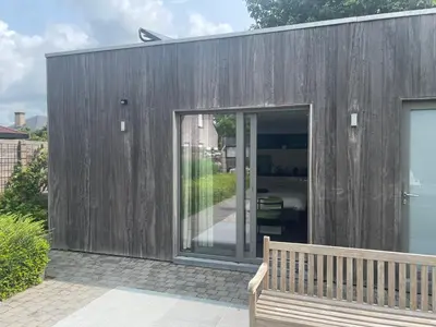 a wooden building with a bench in front of it at Q Studio Green in Herzele
