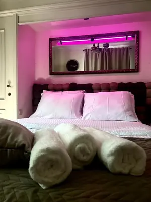 a bedroom with a large bed with pink lighting at Luxury suite with a private terrace in Diest