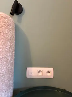 a lightswitch on a wall next to a bed at Le Goujons - New apartment near Midi Station in Brussels