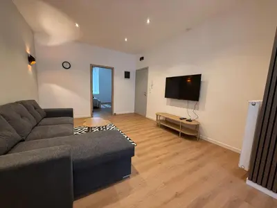 a living room with a couch and a flat screen tv at Le Goujons - New apartment near Midi Station in Brussels